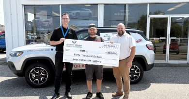 Three people pose with a cheque.