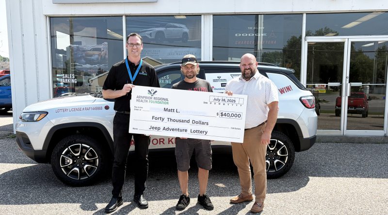 Three people pose with a cheque.