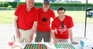 Three people cut a cake.