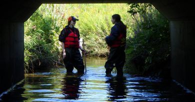 A photo of two people standing in a stream.