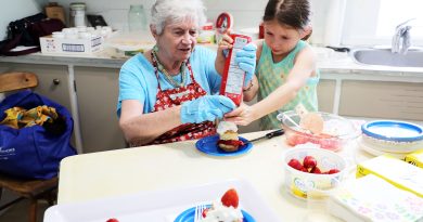 Two people prepare a strawberry shortcake.