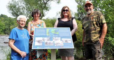 Four people pose by a plaque.