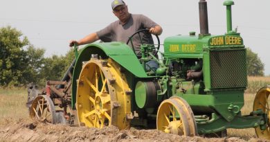 A man plows on a tractor.