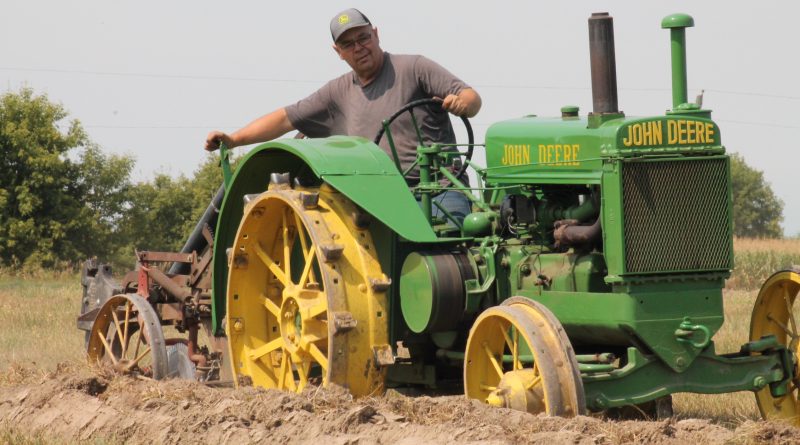 A man plows on a tractor.