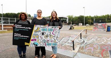 Three people pose at a skate park.