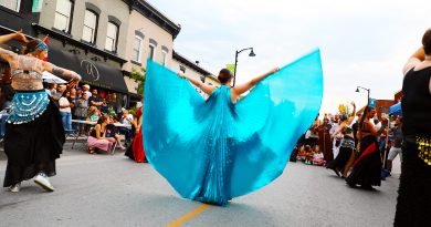 Women perform belly dances on a street.