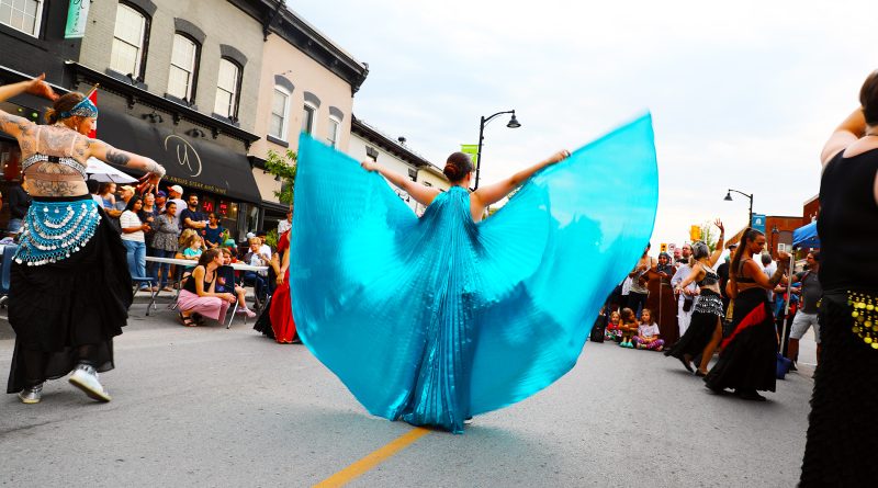 Women perform belly dances on a street.