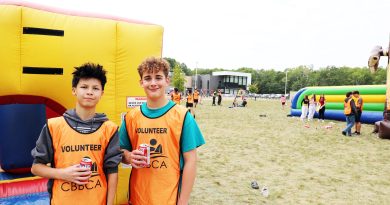 Two volunteers pose in front of a bouncy castle.