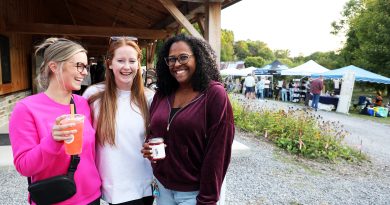 Three women pose in front of a barn.
