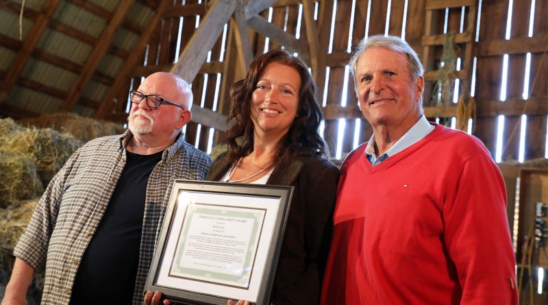 Three people hold an award.