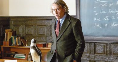 A man stands beside a penguin.
