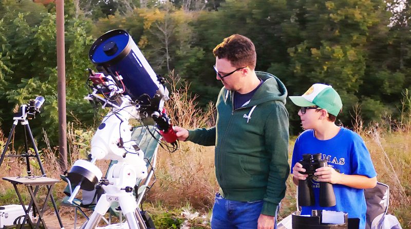 A dad and his son look through a telescope.