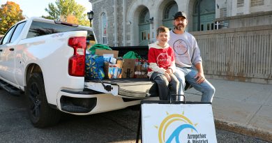 Two people pose with a truckload of food.