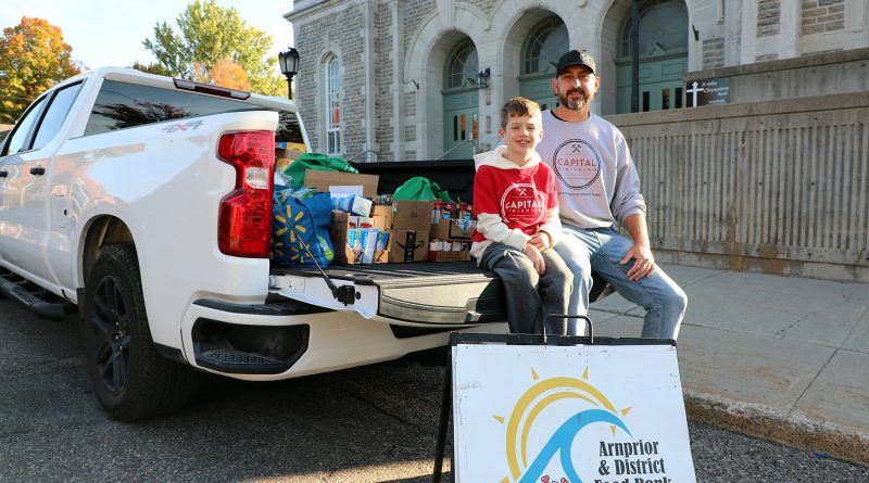 Two people pose with a truckload of food.