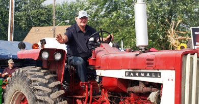 A man on a tractor waves.