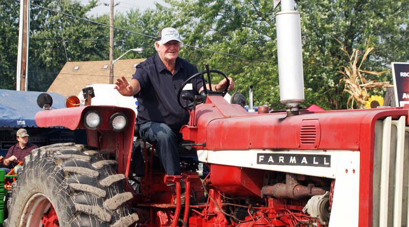 A man on a tractor waves.