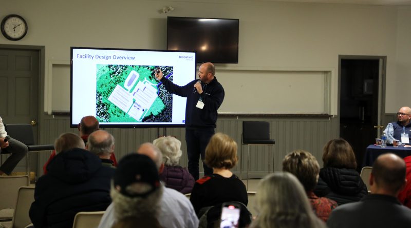 A man speaks to a room full of people.