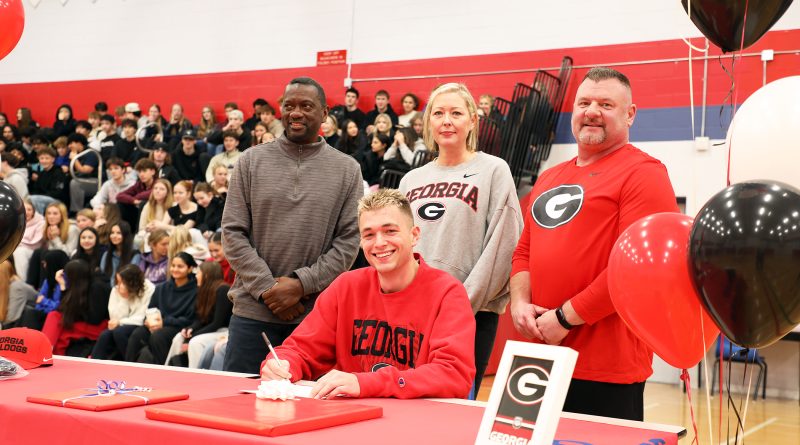 A group of people sign a document.