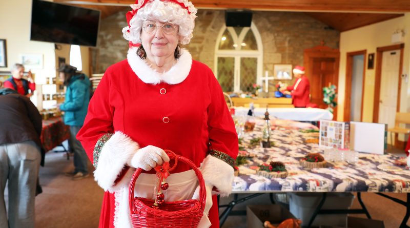 Ms. Claus poses in a room full of shoppers.