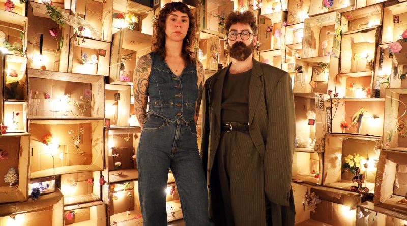 Two artists pose in front of a work.