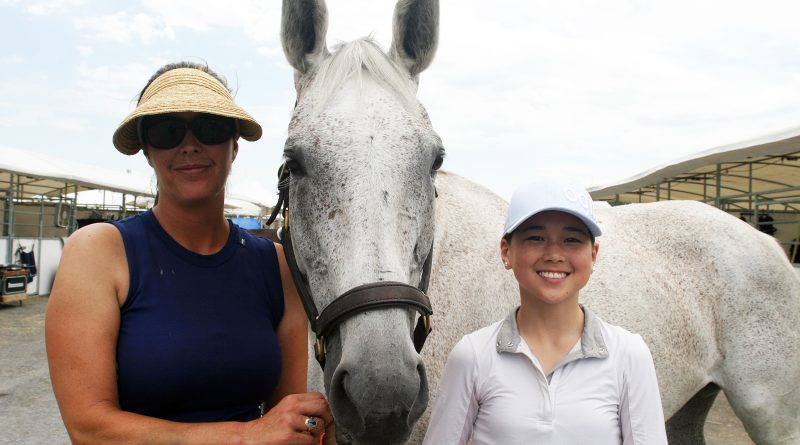 Two people and a horse pose for a photo.