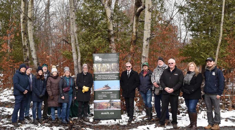 A group of people pose in the woods.