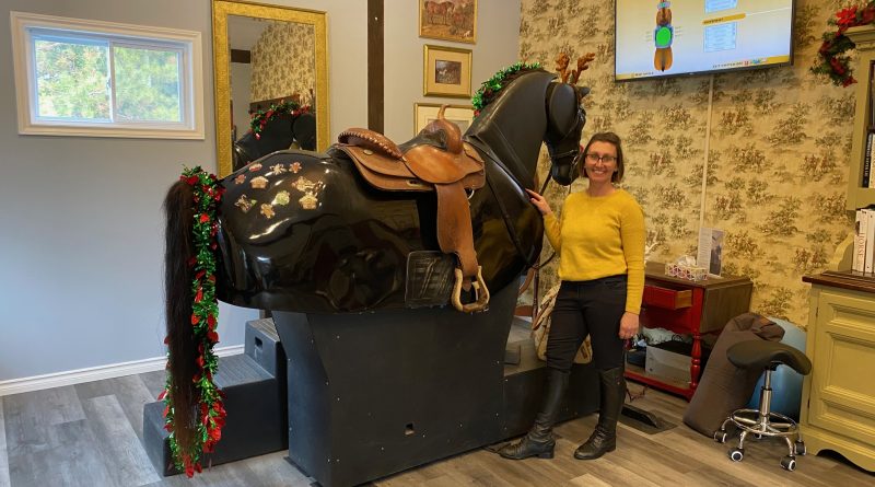 A woman poses next to a mechanical horse.