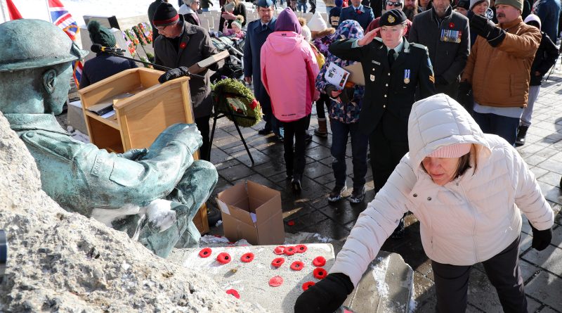 A female solder salutes a war memorial.