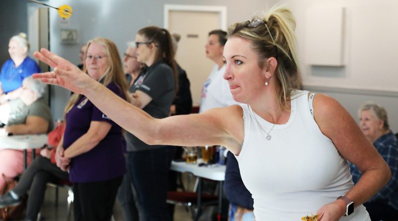 A woman throws a dart.
