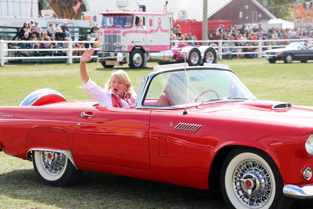 A woman waves from a car.