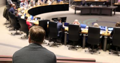 A man watches a council meeting.