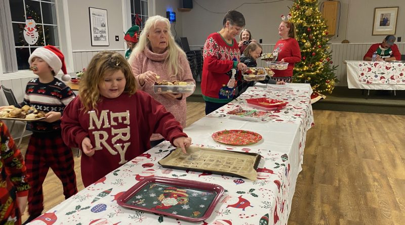 A woman fills a box with cookies.