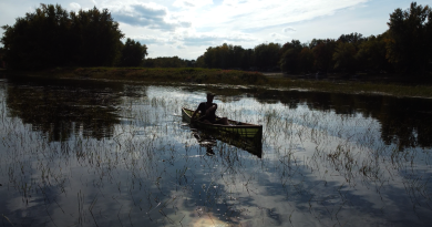 A man peacefully paddles a canoe.