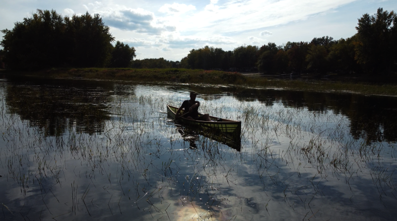 A man peacefully paddles a canoe.