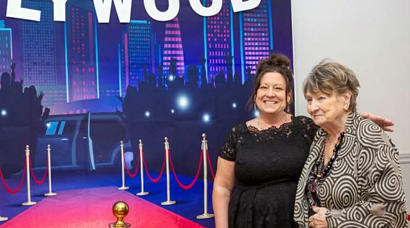 Two people pose in front of a Hollywood sign.