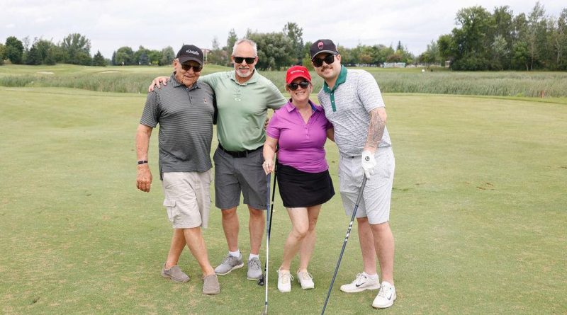 Four golfer pose for a photo.