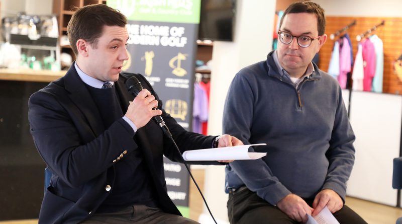 Two people speak at a meeting.