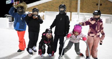 Kids pose on an outdoor rink.