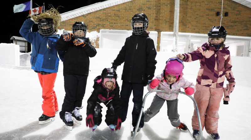 Kids pose on an outdoor rink.
