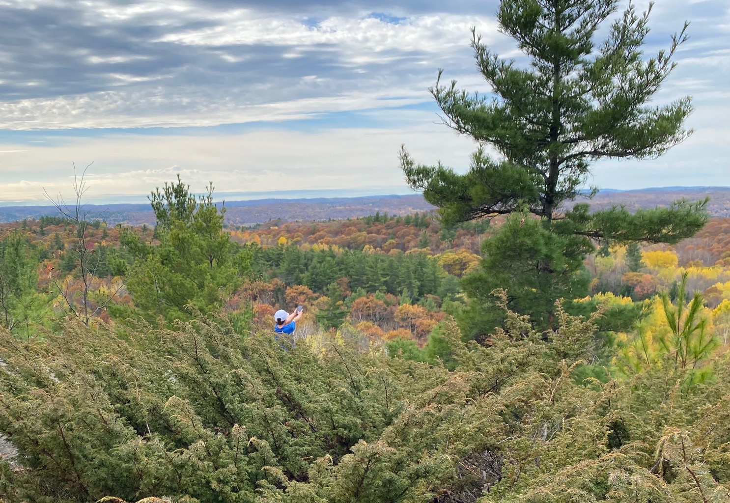 A youth enjoys the view of nature from a small mountain.