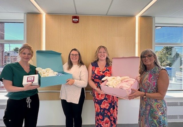 Nurses hold boxes filled with gifts.