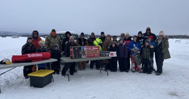 A group of people pose on the ice.