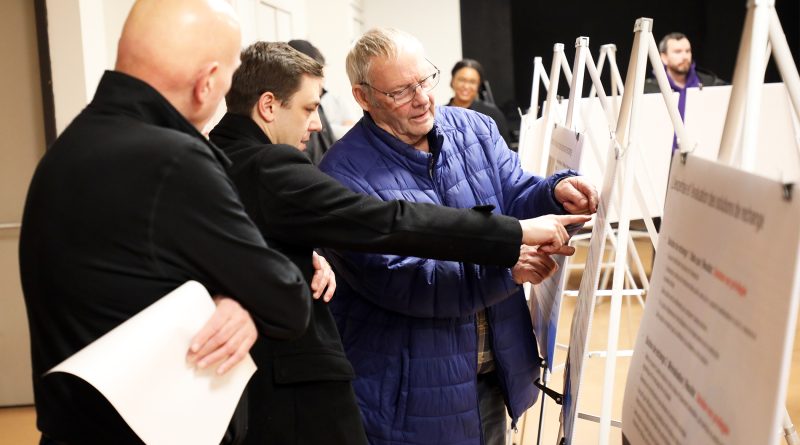Three people chat while looking at a slide.