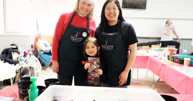 Three people pose in front of garden soil.