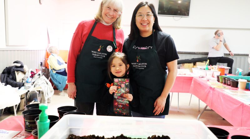 Three people pose in front of garden soil.