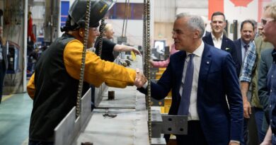 A prime minister shakes a workers' hand.