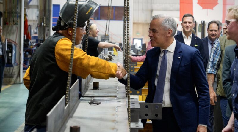 A prime minister shakes a workers' hand.