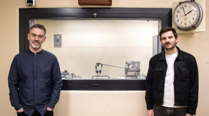 Two people pose in a radio studio.