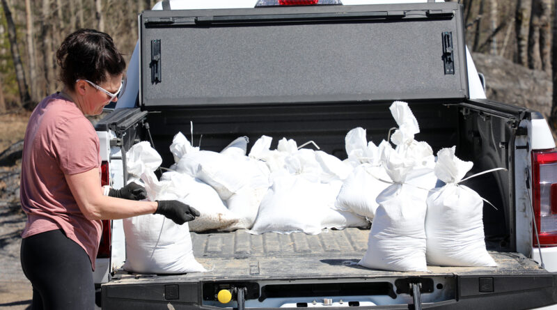 A woman loads a truck with sandbags.