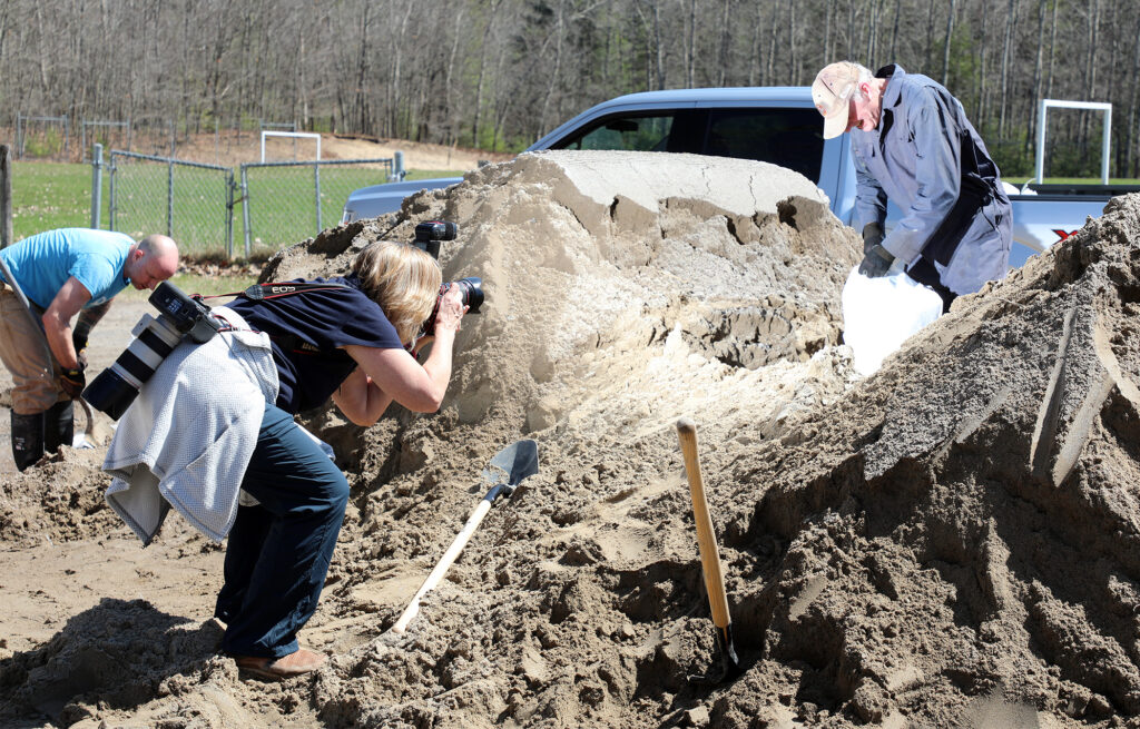 A person takes a photo of a sandbag filler.